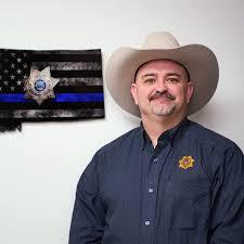 Man in cowboy hat in front of blue line/montana flag